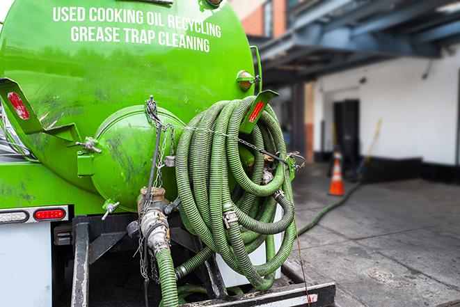 a technician pumping a grease trap in a commercial building in Commerce